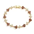 Detailed view of gold-plated clover and butterfly bracelet with red heart-shaped stones. - Gold with Garnet Red Gemstone
