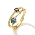 Dettaglio ravvicinato di un anello dorato regolabile con fiori in cristallo blu e nero - Anello Fiore Zirconia Blu Nero Oro