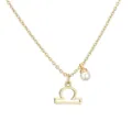 Macro view of a gold Libra zodiac symbol pendant necklace accented with a round white pearl - Libra