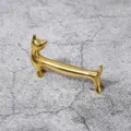 Nahaufnahme eines goldenen Dackel Metall-Essstäbchenhalters mit glänzender Oberfläche. - Gold