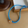Detailed view of blue leather cord necklace with orange flower pendant and crystal - Orange Floral