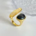 Macro detalle de un elegante anillo dorado con ámbar y piedras negras. - Anillo / Dorado
