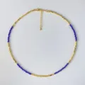 Detailaufnahme einer zarten Gold- und blauem Kristall-Perlen-Halskette von oben. - Blau