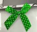 Détail d'un nœud en ruban de satin vert fait main avec d'élégants pois blancs. - Vert