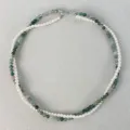 Collana a doppio strato con perle bianche e perle di agata muschiata verde su sfondo materico. - Verde