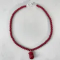 Vista detallada del collar de cuentas rojas con colgante brillante y cierre de T - Collar con Colgante Rojo