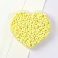 Close-up detail of pale yellow peanut-shaped two-hole beads in a heart-shaped tray - 5x8mm (Approx. 79 Pieces) / Yellow