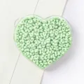 Close-up of mint green peanut-shaped beads for DIY jewelry making in a heart tray - 4x6mm (Approx. 200 Pieces) / 10 Light Green