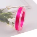 Vista detallada de cordón elástico plano rosa vivo en bobina transparente con tulipanes. - Rosa fuerte