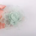 Detailed view of light green sheer organza fabric flower accessory for DIY crafts and apparel. - Light Green