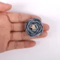 Vue détaillée d'une rose en tissu 3D bleu-gris faite main tenue sur une paume pour l'échelle. - Bleu