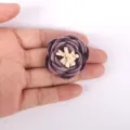 Gros plan détaillé d'une rose en tissu 3D faite à la main avec des bords brûlés - Violet foncé