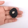 Vue rapprochée d'une rose en tissu noir 3D tenue en main pour référence de taille. - Noir