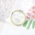 Primer plano detallado de un anillo de resorte de metal beige para manualidades y bolsos. - Blanco Roto