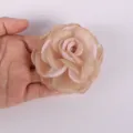 Close-up of a 7.5cm champagne chiffon burnt-edge rose flower accessory held in hand - Gold