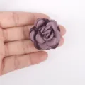 Detailed view of a handmade burned-edge satin rose flower held in hand for scale - Deep purple