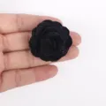 Detailed macro view of a black burnt-edge fabric rose bud held on a palm to show size - Black