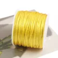 Close-up detail of yellow braiding cord with metallic gold thread on white plastic spool. - Yellow Style 30