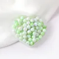 Close-up detail of glossy green AB acrylic round beads in heart tray for DIY jewelry and phone chain - 6mm Size / Color 02 Style