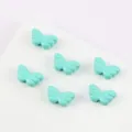 Macro-weergave van zes turquoise vlindervleugelkralen voor het maken van DIY-sieraden - Muntgroen