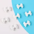 Nahaufnahme von weißen Acryl-Schleifenperlen mit AB-Aurora-Beschichtung für DIY-Schmuck. - 5 Stück / Creme