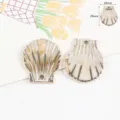 Primo piano di ciondoli in acrilico a forma di conchiglia dorati con dettagli sulle dimensioni. - Guscio (29x24mm) / 1 Pezzo