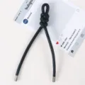 Detailaufnahme des schwarzen geflochtenen Lederbandes als schicker Taschenanhänger. - Schwarz
