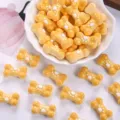 Macro view of cute yellow resin bone-shaped charms with white paw prints for DIY accessories - Light Yellow + White Paw Print