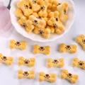 Detailed close-up of cute bone-shaped resin charms with paw print for DIY crafts - Light Yellow + Coffee Paw Print