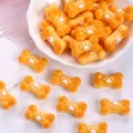 Close-up of orange bone-shaped resin charms with white paw print for DIY crafts - Dark Yellow + White Paw Print