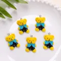 Macro view of five cute yellow teddy bear resin charms on a textured white plate. - Blue Top Black Pants Bear Pendant