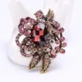 Elegant vintage gold-tone floral brooch featuring a deep red oval gem and pink rhinestones - Pink