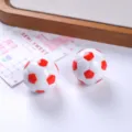 Close-up of glossy red and white resin soccer ball charms for DIY sports jewelry design. - Red