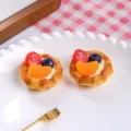 Detailed macro view of two resin simulation fruit egg tarts on a white ceramic plate. - Orange Strawberry Tart