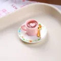 Detailed macro view of a miniature pink resin coffee cup with heart latte art and spoon - Pink Heart Coffee Cup and Plate