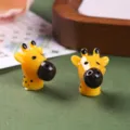Detailaufnahme von zwei gelben Miniatur-Giraffenkopf-Figuren aus feinem Kunstharz - Gelber Giraffenkopf