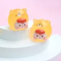 Close-up view of two luminous jelly-colored cartoon tiger charms on a white display stand. - M / Orange Tiger