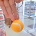 Detalle de cerca de un llavero de pelota de tenis naranja con textura suave - Estilo Tenis / 3.2cm / Amarillo