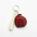Detailopname van een creatieve sleutelhanger met rode honkbalhandschoen en knuppel. - Rood En Zwart Stijl