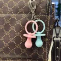 Detail von niedlichen rosa und blauen Schnulleranhängern an einer braunen Tasche - Schnuller / 5CM*2.8CM / Einfarbige Gemischte Schnullerfarben