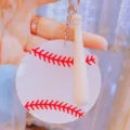 Detailed view of white acrylic baseball keychain with red stitching and mini wooden bat - Keychain / 7.5cm Diameter