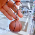 Κοντινό πλάνο ενός ρεαλιστικού καφέ PVC μπρελόκ μπάσκετ που κρατιέται στο χέρι - Θέμα μπάσκετ / Διάμετρος 3.8cm / Καφέ