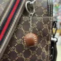 Detailed close-up of a brown faux-leather baseball keychain hanging on a designer style bag - Single Ball Style / Ball Diameter 2.7CM / Brown