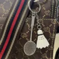 Close-up van een creatieve badmintonracket en shuttle-sleutelhanger op een bruine handtas - Badminton Racket (White) / Wit
