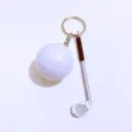 Macro detail of a mini white golf ball and silver club keychain with black grip charm - Golf