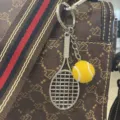 Κοντινό πλάνο ενός μπρελόκ μίνι ρακέτα και μπάλα τένις σε μια τσάντα με σχέδια - Μπάλα Τένις / Κίτρινο