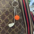 Golfclub en oranje bal sleutelhanger hanger aan een luxe tas met een designpatroon - 8.5cm / Oranje
