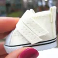 Nahaufnahme eines 5 cm langen cremefarbenen Segeltuch-Puppenschuhs mit Klettverschluss - 5x2.5x3cm / Weiß