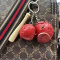 Red leather baseball keychain charm with mini wooden bat on a brown bag - Yellow Ball Dark Red Glove Black Strap