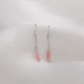 Nahaufnahme von eleganten rosa Erdbeerquarz-Ohrhängern mit silbernen Haken und feinen Ketten. - Weißgold